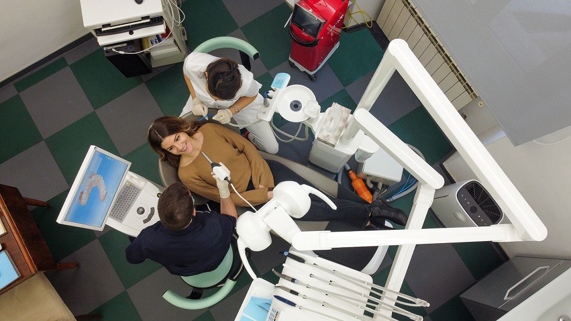 Una visita vista dall'alto: la paziente in poltrona, il dentista e l'assistente